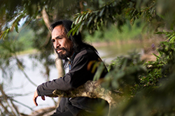 Domingo Ankuash entre la vegetación, a la orilla de un río. Foto: Edu León